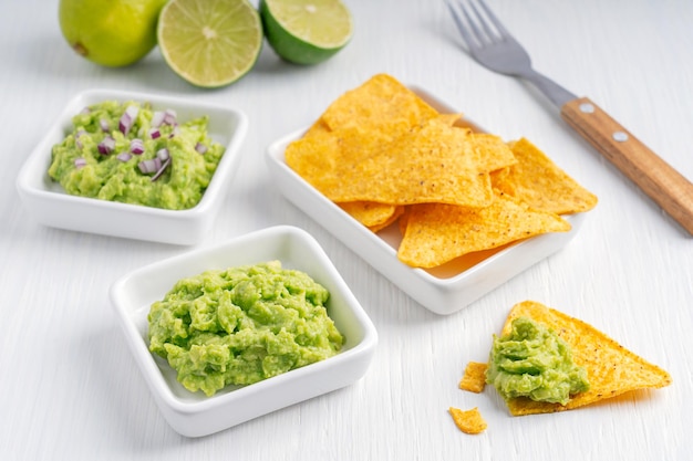 Vegetarian mexican guacamole dipping sauce made of pureed avocado served with nachos on wooden table