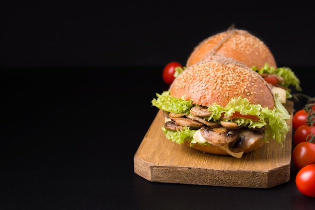 Vegetarian mushroom sandwich close-up on a black background. next to the tomatoes. Have copy space