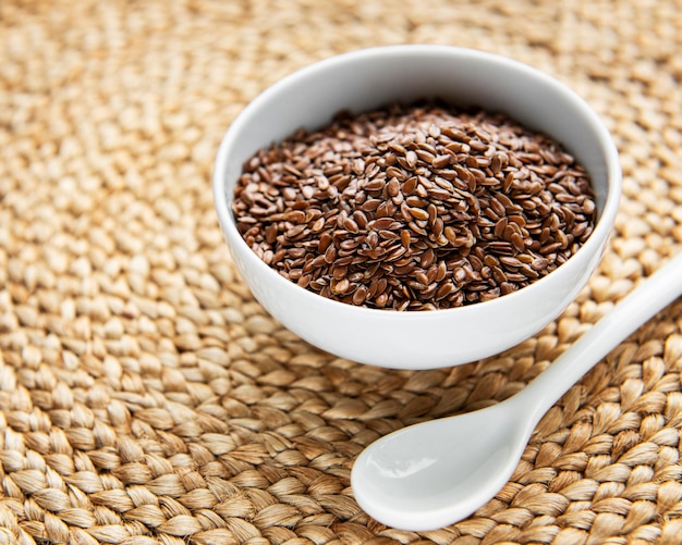 Vegetarian organic nutrition flax seeds in bowl on vintage straw mat background