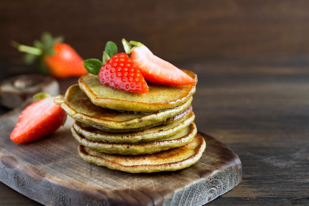 Vegetarian pancakes with ripe strawberries. on a wooden table.