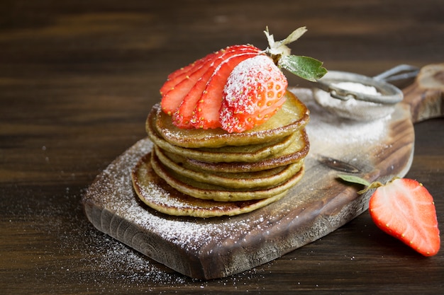 Vegetarian pancakes with ripe strawberries. on a wooden table.