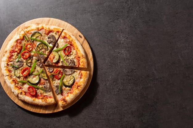 Vegetarian pizza with zucchini tomato peppers and mushrooms on black stone