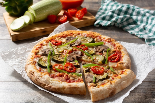 Vegetarian pizza with zucchini tomato peppers and mushrooms on wooden table