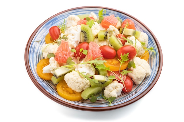 Vegetarian salad of cauliflower cabbage, kiwi, tomatoes, microgreen sprouts isolated on white background. Side view, close up.