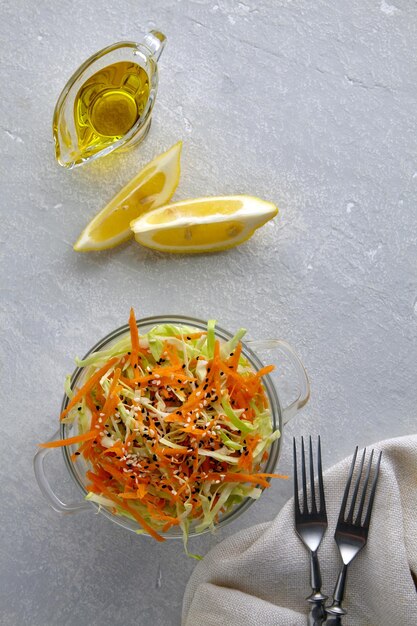 Vegetarian salad of white cabbage and carrots seasoned with olive oil and lemon juice Healthy coleslaw salad in a bowl on a gray concrete table