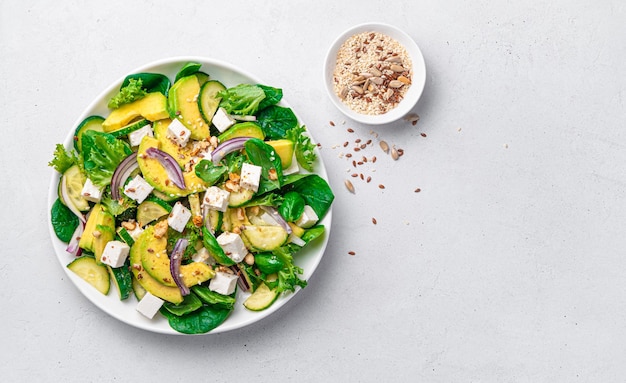 Vegetarian salad with avocado herbs and feta on a light background with space to copy Healthy food