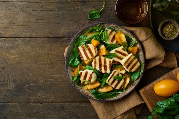 Vegetarian salad with circassian halloumi cheese tomatoes spinach and nuts on wooden background