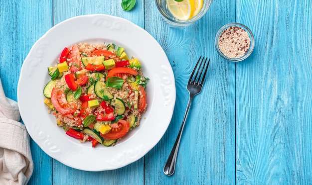 Vegetarian salad with quinoa fresh vegetables and herbs on a blue wooden background Top view copy space