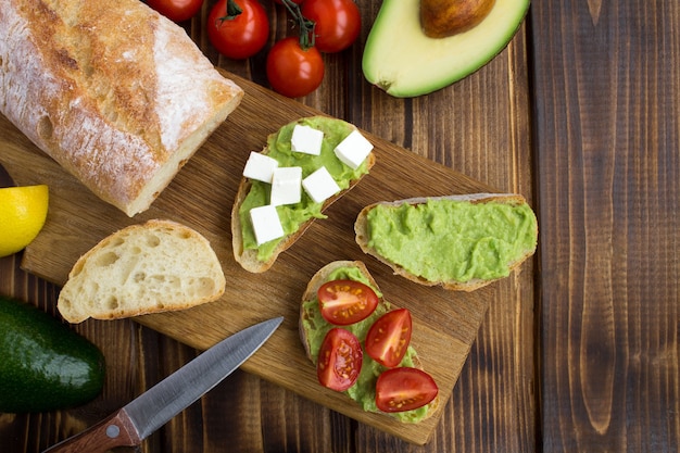 Vegetarian sandwiches with avocado,cherry and soft cheese  on the brown  wooden background.Top view.Copy space.