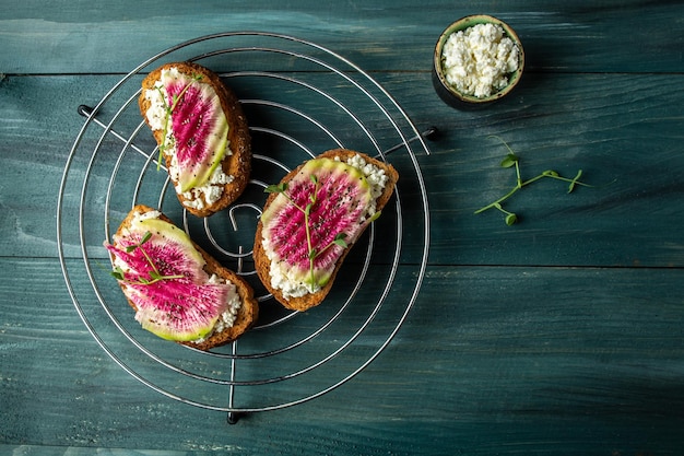 Vegetarian toasts from sliced watermelon radish and goat cheese banner catering menu recipe place for text top view