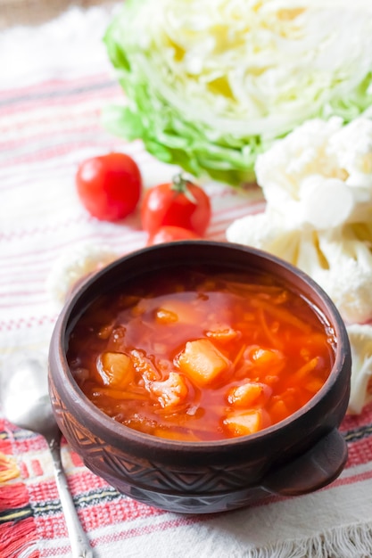 Vegetarian tomato soup with cabbage and cauliflower in a ceramic rustic bowl