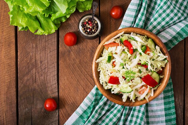 Vegetarian vegetable salad (cabbage, tomato, paprika, cucumber, onion) in a wooden bowl