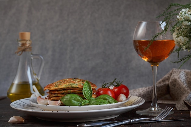 Vegetarian zucchini fritters served with fresh herbs tomatoes and garlic Romantic dinner with wine