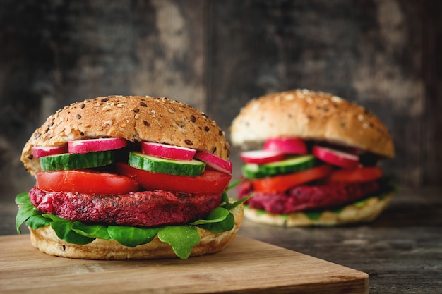 Veggie beet burger with lamb's lettuce, tomato, radish and cucumber on rustic wooden table