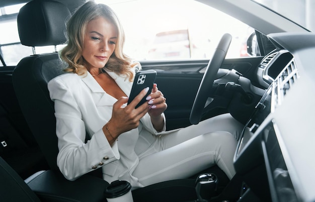 Vehicle interior Woman in formal clothes is indoors in the autosalon