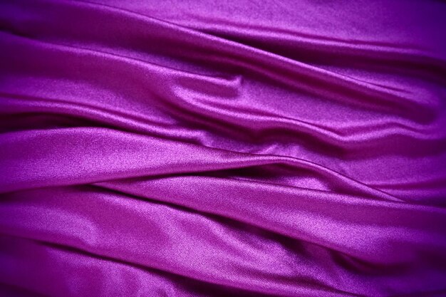 Velour fabric similar to silk textiles in a folds and beautiful waves purple pink magenta shades on