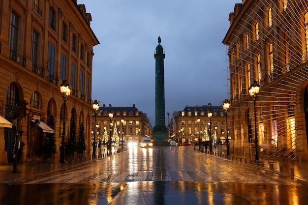 Vendome column with statue of Napoleon Bonaparte on the Place Vendome decorated for Christmas at rainy night Paris France