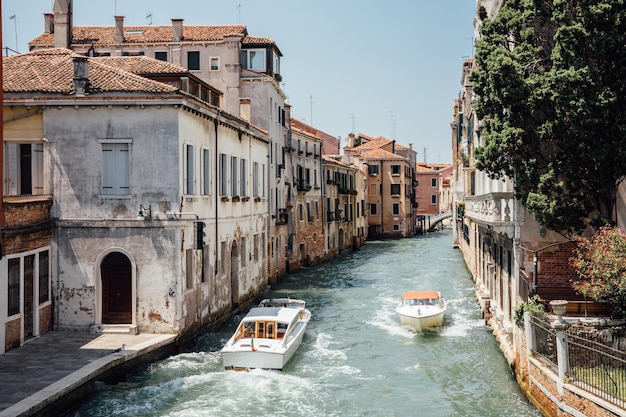 Venice, Italy - July 1, 2018: Panoramic view of Venice narrow canal with historical buildings and boats traffic from Bridge Foscari. Landscape of summer sunny day and blue sky