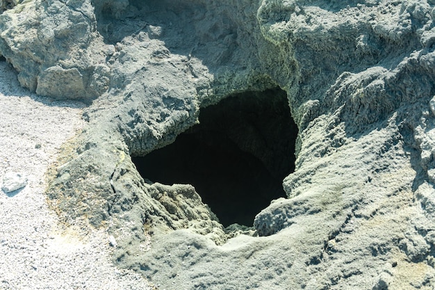 Vent of a volcanic fumarole in the ground covered with crystalline sulfur