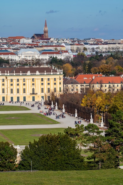 Verical cityscape with half of buildings Schonbrunn Palace in Vienna, Austria and roofs of other historical houses on a background of blue sky on an autumn day.