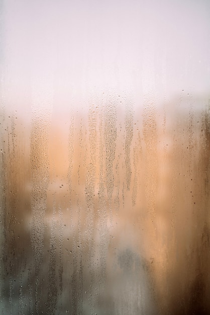 vertical background texture of a wet window in drops with sun after rain warm photo high quality