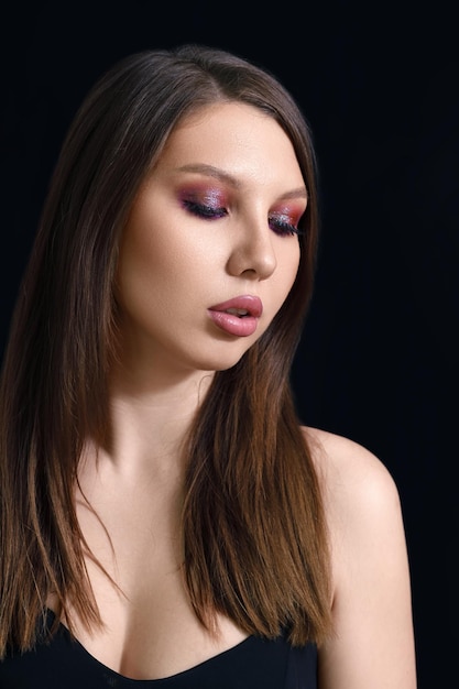 Vertical beauty portrait of a brunette woman on a black background