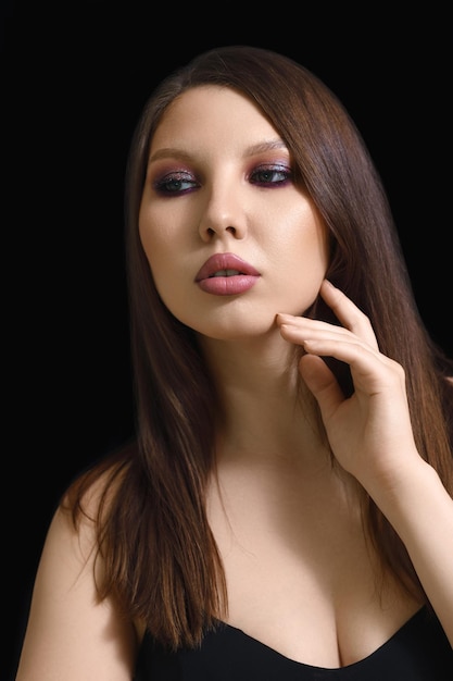 Vertical beauty portrait of a brunette woman on a black background