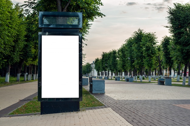 Vertical black billboard with blank space. mockup with a white background, for use in advertising. morning park without people and with green trees.