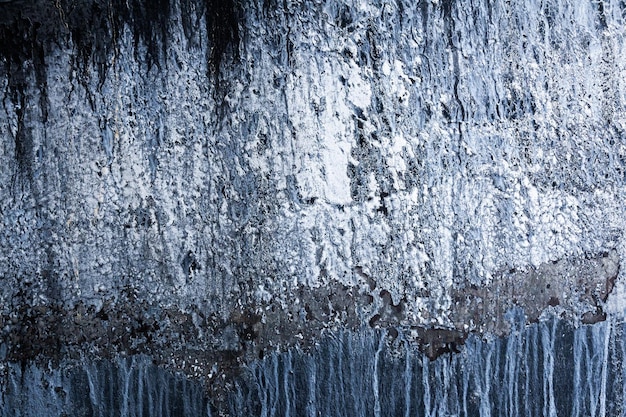 Vertical black rock with ice and snow Abstraction of an icy rock with snow