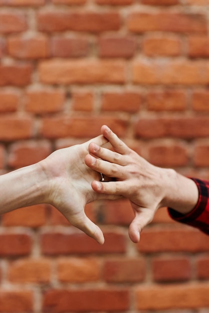 Vertical close up of two male hands greeting each other with special handshake against brick wall