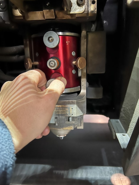 Vertical closeup of the hand of an unrecognizable person adjusting the lens of CNC machine laser cut