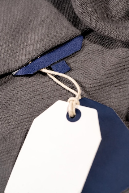 A vertical closeup shot of white blue tags on a string on a cloth with a blank blue tag on the neck