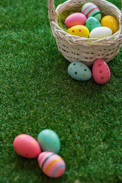 Vertical Easter background with colorful yellow pink blue Easter eggs in woven basket and green grass Top view with copy space Easter holidays social media background