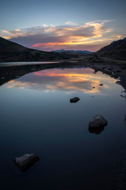 Vertical format photo of sunset on a mountain lake with cloud reflections on the crystal clear water