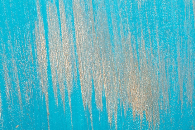 Vertical Golden brush strokes on turquoise background. Dry brush technique. Place for your design.