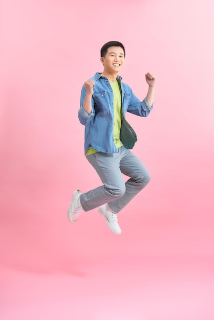 Vertical image of happy man jumping in studio  over pink background