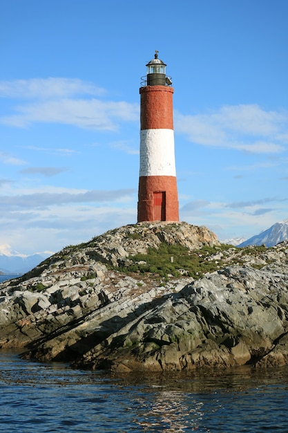 Vertical image of red and white striped Les Eclaireurs lighthouse on a rocky islands, Beagle channel, Ushuaia, Argentina