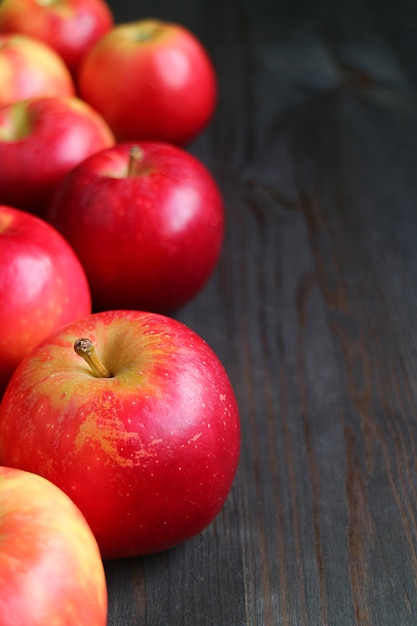 Vertical image of Rows of fresh ripe red apples on black wooden background