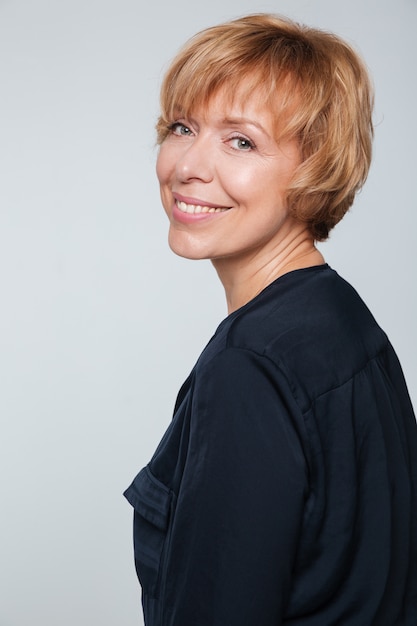 Vertical image of smiling elderly woman standing sideways