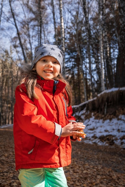 Vertical lifestyle portrait of preschool aged smiling girl in late autumn forest