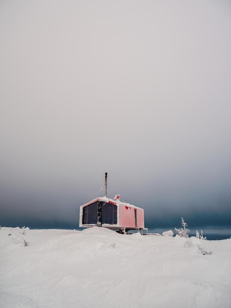 Vertical minimalistic background with of lonely red cabin in winter under dramatic sky Dubladom on the mountain Volodyanaya Kandalaksha Murmansk region in Russia Copy space