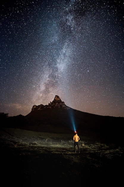 Photo vertical night photograph of an illuminated man looking at the stars