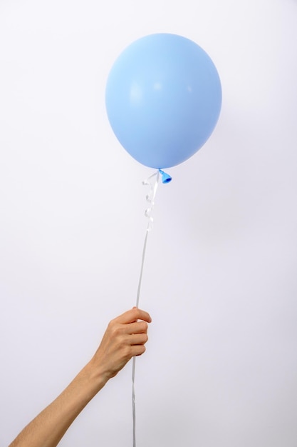 Vertical one minimal blue balloon in hand on white background copy space element of decorations for birthday party wedding festival