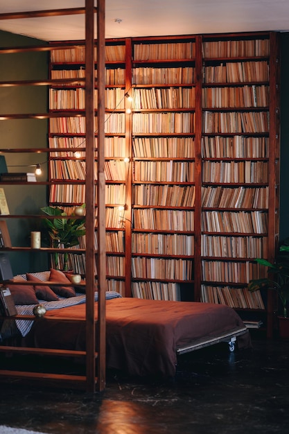 Vertical photo of bedroom in an interior large bookshelf up to ceiling with parquet flooring