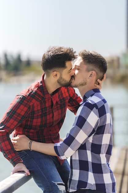 Vertical photo of a gay couple kissing on a jetty