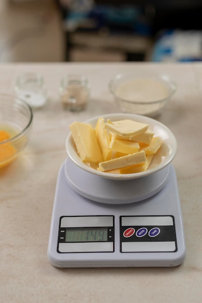 Vertical photo of a gramera scale with butter weighing to prepare bread