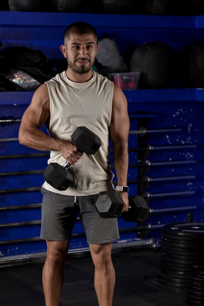 Vertical photo of a latino man with weights doing bicep exercises with a pair of dumbbells and copy space