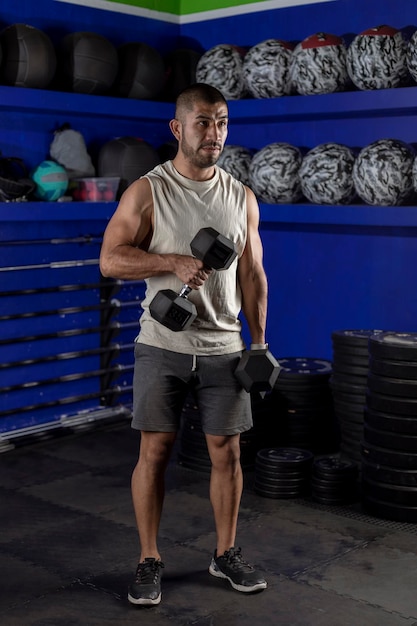 Vertical photo of a latino man with weights doing bicep exercises with a pair of dumbbells and copy space