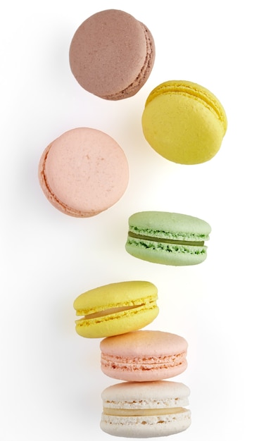 Vertical photo of Macaroon. Colorful cake macaron with pastel tones fall at the stack macaroon on white surface. Top view of almond cookies.