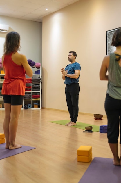 Vertical photo of a mature man teaching samasthiti pose to a group of students